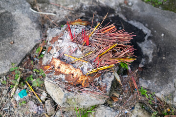Remains of burnt incense sticks on a stone altar, likely used for ritual or prayer offerings in a local spiritual or religious practice.