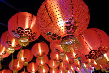 Vibrant red lanterns illuminate night sky, creating festive atmosphere with intricate floral...