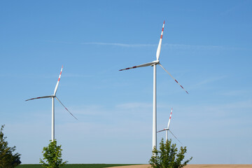 Three modern wind turbines in the countryside under a clear blue sky. Austria.