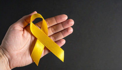 Hand holding yellow awareness ribbon. Support for military troops, suicide prevention awareness