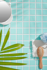 Minimal bathroom layout with palm leaves, wooden brush, towel and sponge on blue tile. Area beside...