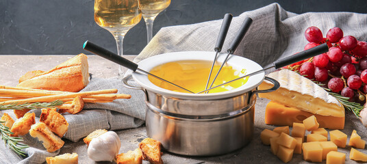 Cheese fondue and different snacks on grunge background