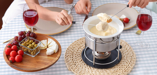 Young couple dipping croutons into cheese fondue at home