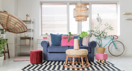 Interior of stylish living room with blue sofa, poufs and plants