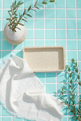 Bathroom setup with mosaic tile floor, soft towel and empty tray under sunlight. The clean layout...