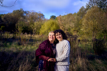 middle-aged daughter and elderly mother together on a walk in the autumn forest
