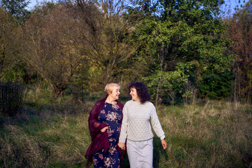 middle-aged daughter and elderly mother together on a walk in the autumn forest