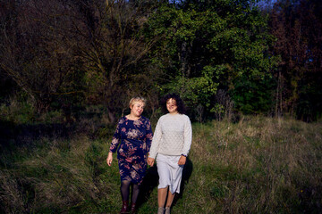 middle-aged daughter and elderly mother together on a walk in the autumn forest