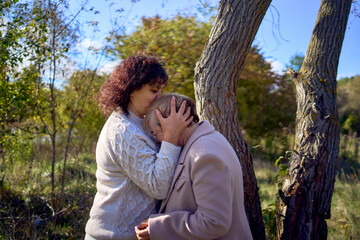 a   middle-aged daughter and elderly mother together on a walk in the autumn forest