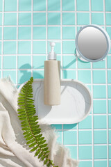 Minimal bathroom layout with white tray, beige bottle and towel draped gently over soft tiles....