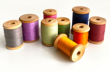 Vintage wooden spools with colorful threads on a white background.