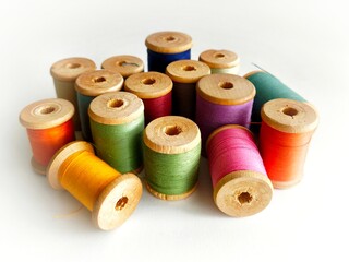 Colorful sewing threads on assorted wooden spools on white background
