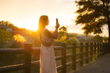 Girl holding phone capturing scenery in warm sunlight