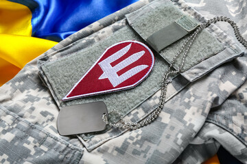 Badge with trident on military uniform and flag of Ukraine, closeup