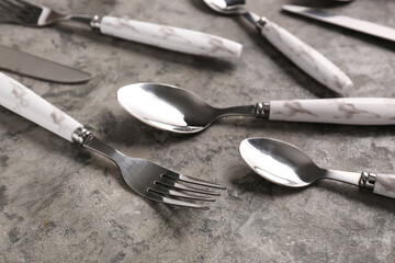 Stainless steel set of cutlery with plastic handles on grey background