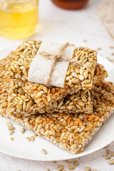 Plate with tasty kozinaki and jars of honey on white background