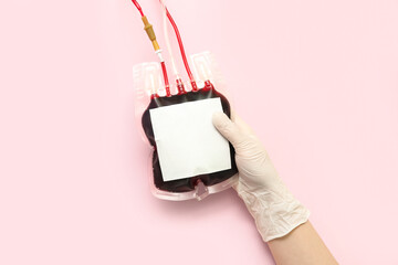 Female doctor with blood pack on pink background. World Donor Day