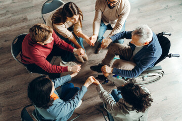 Diverse group of people holding hands in circle during therapy session