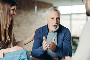 Senior man sharing concerns during therapy session with psychologists