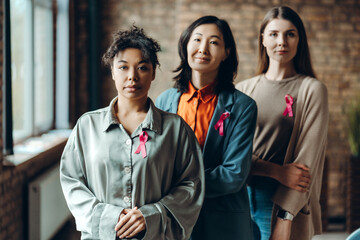 Group of three women wearing pink ribbons showing support for breast cancer awareness