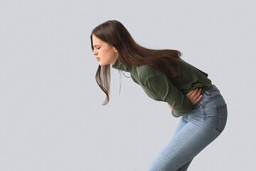 Young woman suffering from stomach ache on light background
