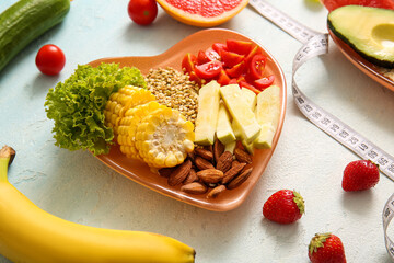 Plate with fresh healthy products and measuring tape on light background, closeup. Diet concept