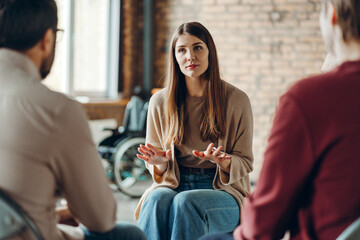 Young woman leading group therapy session discussing mental health