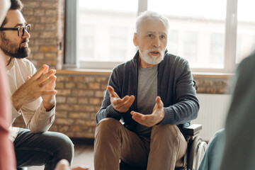 Senior man in wheelchair sharing his story during group therapy session