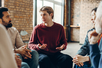 Attractive man sharing problems during group therapy session