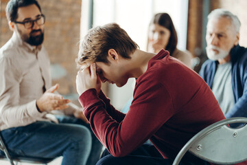 Young man suffering from depression during group therapy session