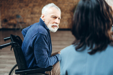 Senior man in wheelchair talking with doctor in hospital room