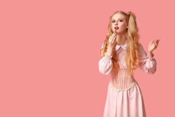Beautiful young woman dressed as doll with lipstick on pink background