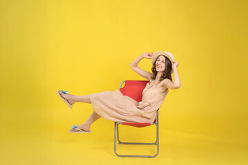 Cheerful Woman Relaxing on a Chair Against Vibrant Yellow Background