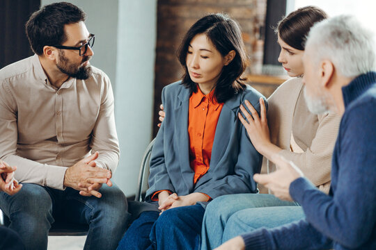 Teammates comforting sad businesswoman during group therapy session