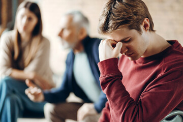Young man suffering headache during family quarrel at home