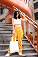 Vibrant sporty girl holding canvas bag on outdoor stairs