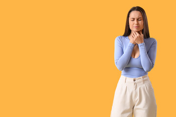 Young woman suffering from sore throat on yellow background