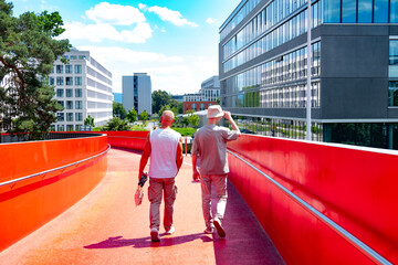Two men walking together, Happy Mature friends walking on red urban bridge, Older father and young...
