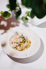 Delicious pasta dish served on a stylish white plate with fresh herbs