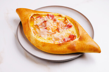 Delicious khachapuri filled with cheese and bacon on a plate