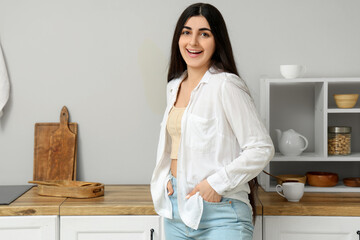 Beautiful young happy woman in kitchen at home