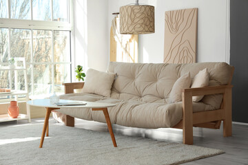Light interior of modern living room with comfy sofa, coffee table and lamp