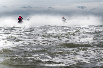 Jet skiers race through a stormy, churning sea, creating dramatic splashes, capturing an...