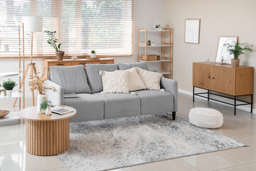 Interior of stylish living room with grey sofa and coffee table near window