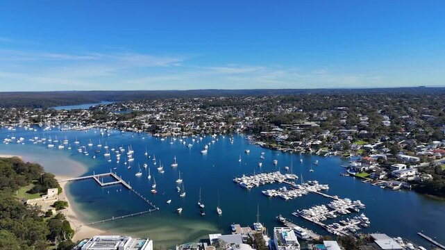 Wide panoramic establishing aerial of Cronulla harbor and boats anchored offshore with urban coastline, Sydney NSW Australia