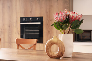 Dining table with protea flowers in vase and decor in kitchen. Closeup