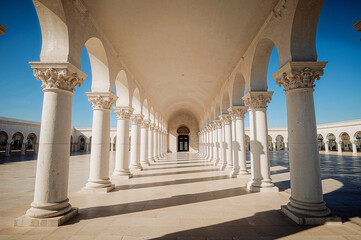 Sunlit white colonnade opening to a clear sky