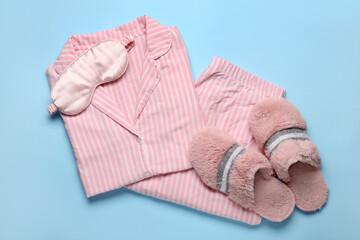 Stylish female pajamas, sleeping mask and slippers on color background
