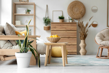 Bowl with lemons on table in light living room interior