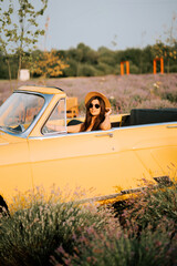 Woman enjoying sunny day in yellow convertible among lavender fields